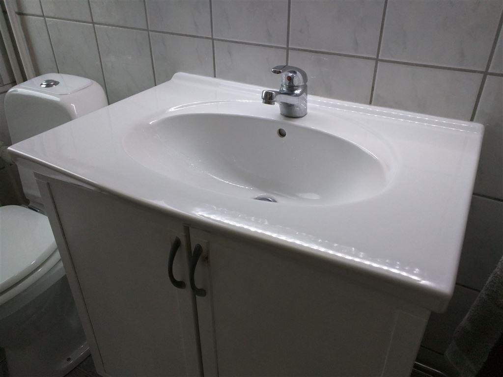 Vitt handfat med kran och vit fristående toalett stol, badrum ...