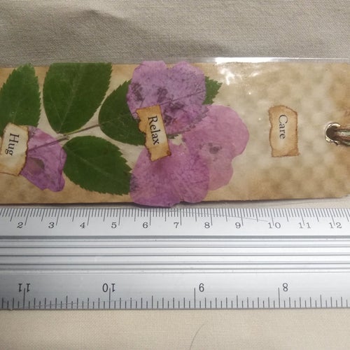 1 Bokmärke torkade växter på kaffe färgat papper, laminerat, ca 4,5cm x 13,5 cm