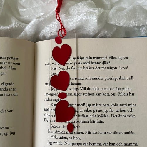 Bokmärke med röda hjärtan och tofs