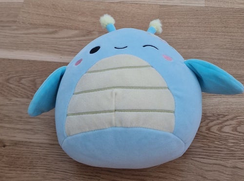 Blå Squishmallow-liknande mjukdjur med vingar och antenner