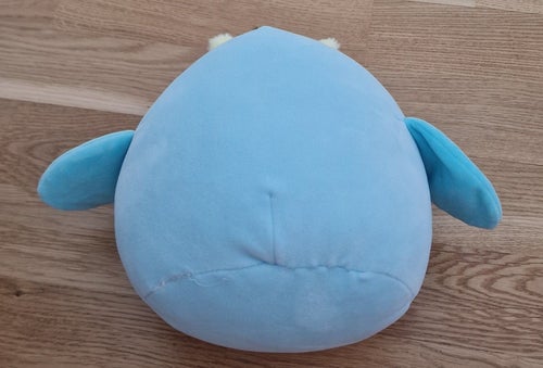 Blå Squishmallow-liknande mjukdjur med vingar och antenner