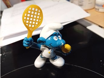 Smurf med tennisracket och boll