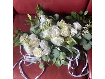Konstgjort blomsterarrangemang med vita rosor och gröna blad