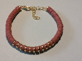 ett egenhändigt gjort armband. I färgerna guld och ljus tegel.