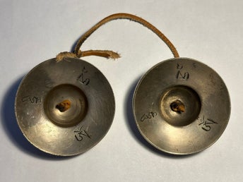 Ett par tibetanska tingsha-cymbaler, tingshaw i mässing med läderband